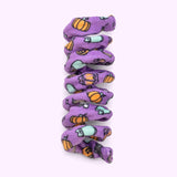 Close-up of purple spiral cat toy that has a pattern of Zombie Pusheen and Bat Pusheen with orange pumpkins and black stars.