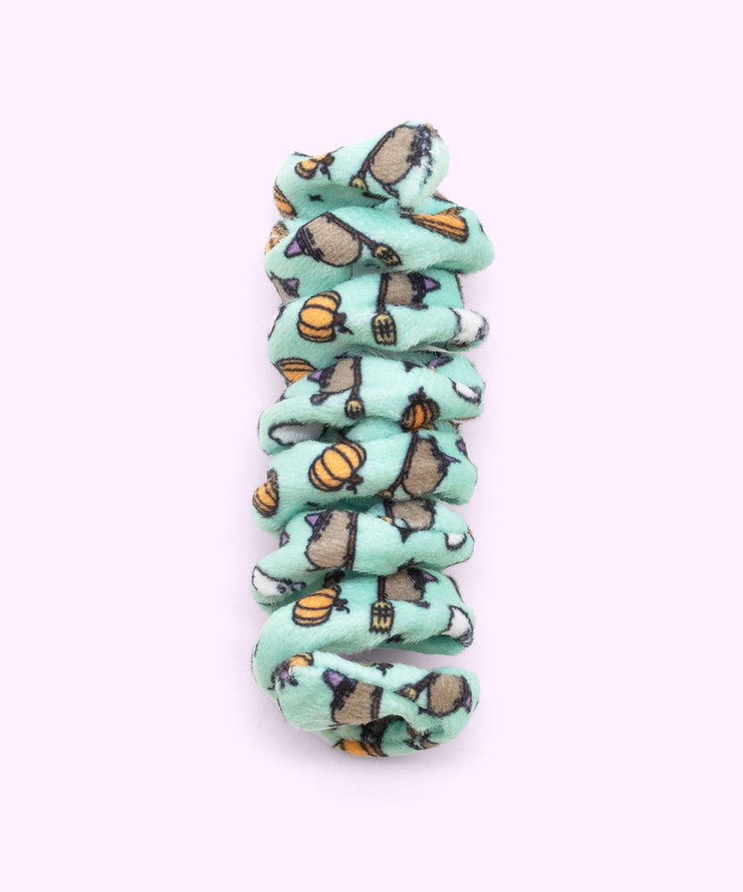Close-up of mint green spiral cat toy that has a pattern of Witchsheen wearing a purple hat and riding a broom surrounded by pumpkins and ghosts.