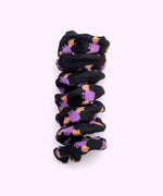 Close-up of black spiral cat toy that has a pattern of a purple and orange Batsheen.
