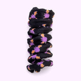 Close-up of black spiral cat toy that has a pattern of a purple and orange Batsheen.