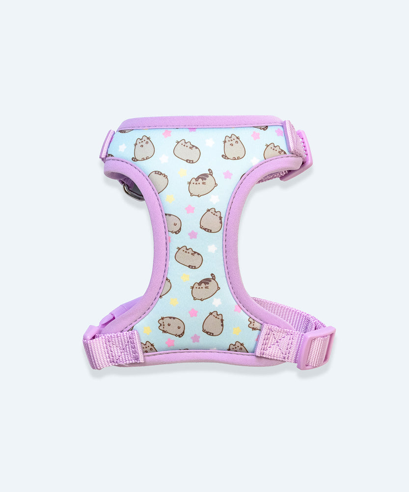 Under view of the Pusheen Pet Harness. The interior is light blue with an all over pattern of three Pusheens and yellow, pink, purple, and white stars. The Pusheen poses show the cat waving, loafing, jumping, and standing.