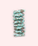 Close-up of mint green spiral cat toy that has a pattern of Pusheen the Cat holding a cup of tea surrounded by tea cups and kettles.