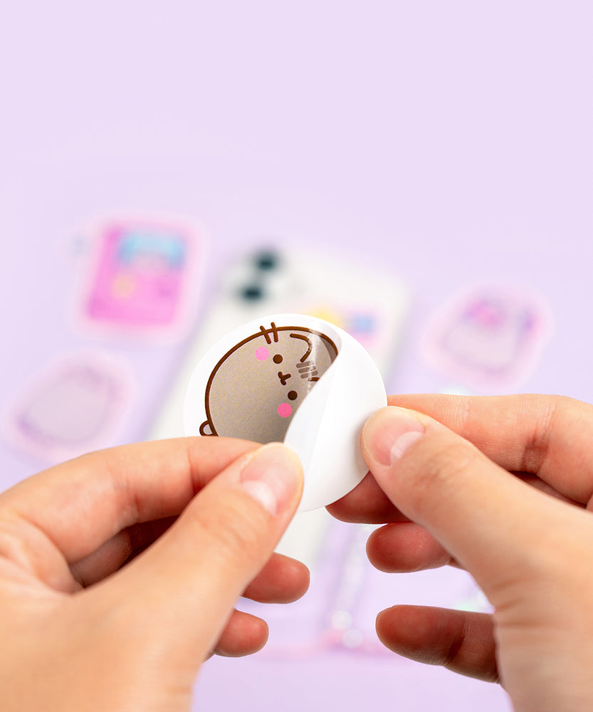 Pusheen Phone Stickers shown next to a phone to show the size of the stickers. 