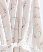 Pusheen Plush Robe hangs on a hanger and shows a close-up of the all over gray cat print on the cream fabric. 