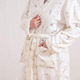 Model wearing a cream-colored Pusheen Plush robe with large all over pattern of a lying down cat. Pusheen's classic striped tail, back stripes, and facial features can be seen in full detail. 