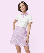 Model wearing the white and purple collared Pusheen Purple Polka Dot Dress. The purple collar of the dress sits atop a white, short sleeve top portion. The bottom skirt portion is purple with repeating white polka dots and grey Pusheens. 