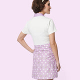 Model shows off the back of the purple Pusheen Dress. The purple polka dot shift dress has a white short-sleeve top and purple skirt bottom.