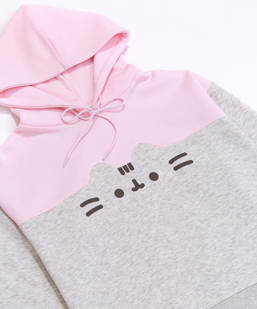 Front view of the Pusheen Relaxed-Fit Character Hoodie lying on a white surface. The two-toned sweatshirt has a light pink hoodie and chest coloring while the sleeves and bottom of the sweatshirt are light heather gray. 