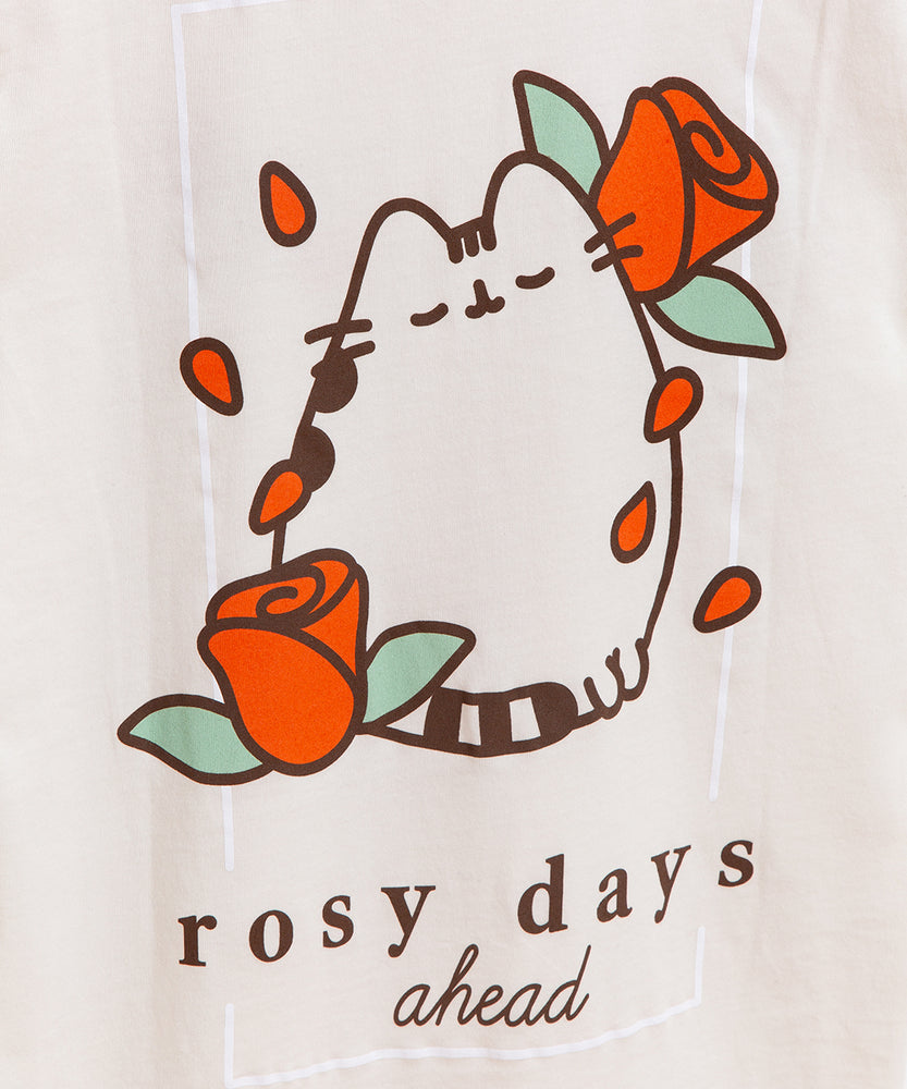 The front and back view of the Pusheen Rosy Days Unisex Tee set at an angle. The vintage white short-sleeve tee lies against a light green background. The t-shirt has two graphics on it: one of Pusheen in the top right of the front of the tee and a large print on most of the back of the tee. 