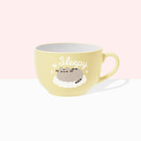 Front view of the Pusheen Sleepy Mug. The rounded light-yellow mug is perfect for lattes. The exterior has a light-yellow handle with white interior walls. The outside of the mug features Pusheen the Cat sleeping on a fluffy, white cloud surrounded by sparkles and the slogan “sleepy.” 
