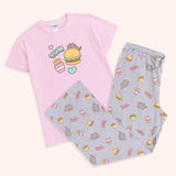 The Pusheen Snack Time Pajama Set has a short sleeve light pink graphic pajama top and light grey lounge pants. The tee has a graphic of Pusheen surrounded by her favorite snacks in the center of the t-shirt. The lounge pants are covered in an all over print of Pusheen, fries, hamburgers, and the phrase “YUM.”  
