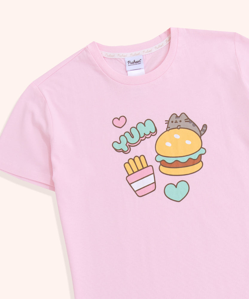 A close-up of the graphic on the front-center of the light pink, unisex pajama top. The grey and brown tabby cat is accompanied by a yellow, green, and brown hamburger, pink and mint green hearts, and yellow, pink, and white fry's packet. 