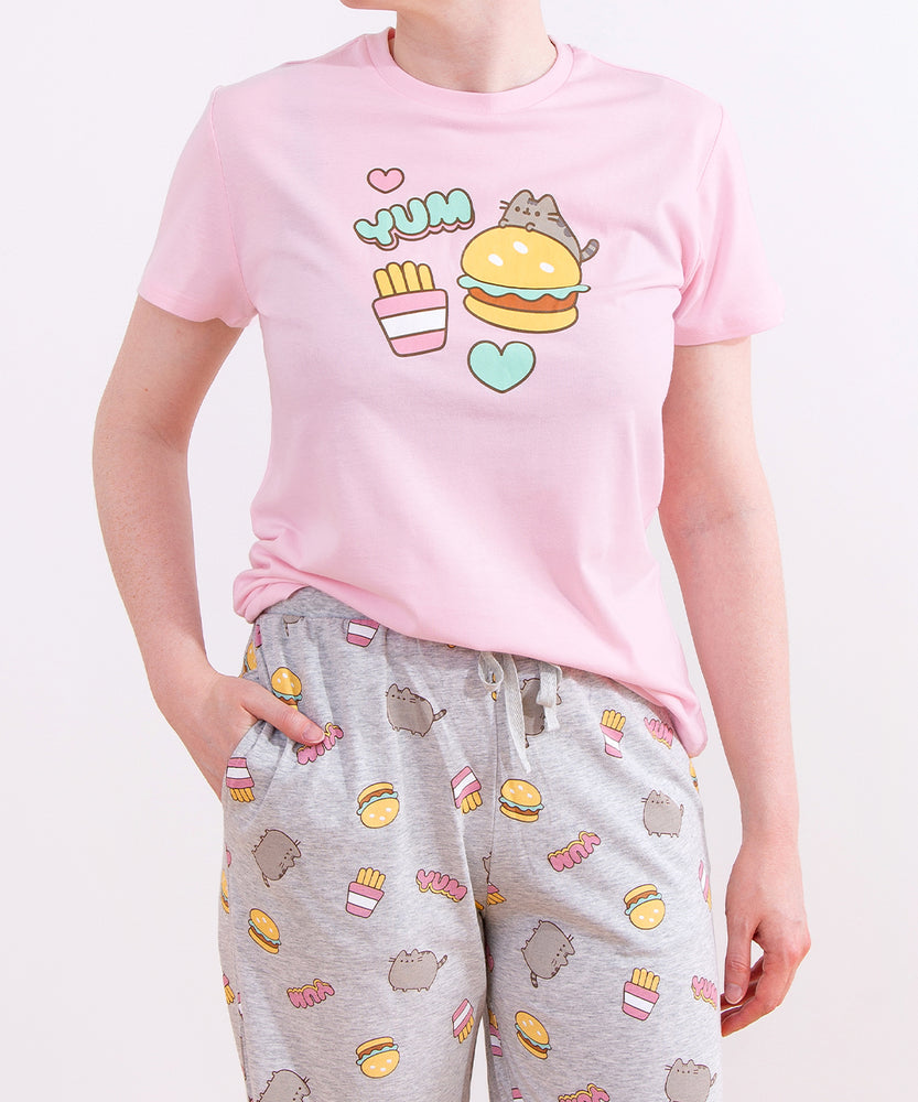 Model wearing Pusheen Snack Time Pajama Set. The pink unisex pajama top graphic matches the all over print pattern on the light grey lounge pants.