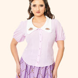 Model wears Pusheen Springtime Blouse untucked. The button closure runs down the mid front of the blouse with purple buttons that match the color of the blouse.