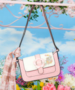Pusheen Springtime Purse hangs off a wire railing. Tied to the strap of the purse is the Pusheen Springtime Scarf. The pink scarf features an all over print of Pusheen in a bouquet of flowers.