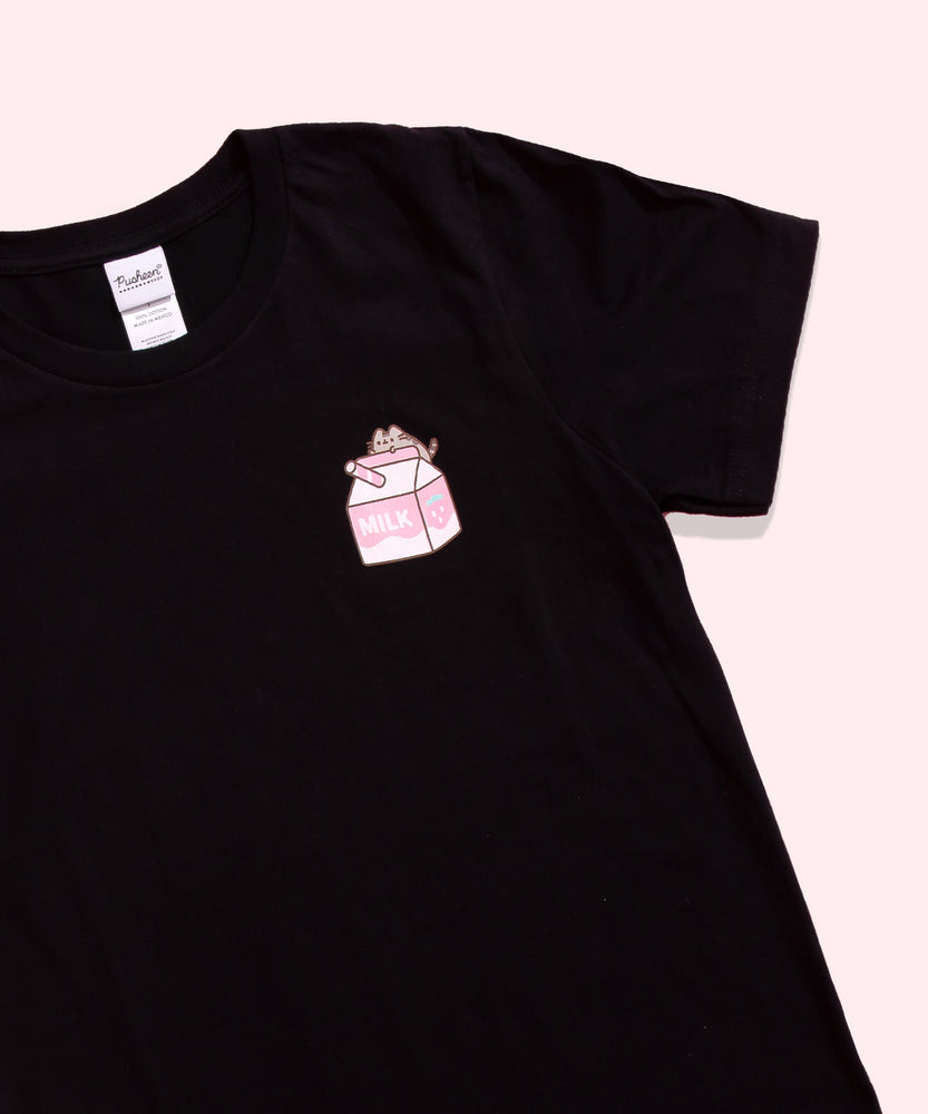 Close-up view of the short sleeve black graphic. Pusheen sits atop a white and pink strawberry milk carton. The grey tabby cat face, paws, and tail have grey and brown details.