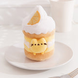 Front view of the Pusheen Sweets Lemon Cake Plush. The removable yellow Pusheen plush sits within a cake environment with whipped topped and a yellow lemon slice. 