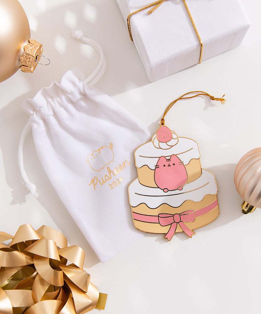 Strawberry cake ornament lies on top of its accompanying white storage bag. The white color of the bag matches the white icing on the cake. 