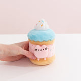 Model's hand holding Pusheen Sweets Sprinkle Cake Plush 2-pc Environment. The birthday cake plush has a layered cylinder base with whipped topping.
