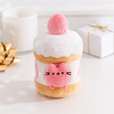 Front view of the Pusheen Sweets Strawberry Cake Plush. The removable light pink Pusheen plush sits within a cake environment with whipped topped and a light pink strawberry at the very top.  