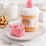 Side view of the Strawberry Plush. The removable interior plush rests in front of the cake environment. The little pink plush fits inside the front hole of the cake plush.