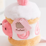 Close-up view of the Pusheen Label logo hangtags. The light pink tags feature the Pusheen the Cat logo on the circle sticker while Pusheen’s face is embossed in the rectangular shaped tag.  