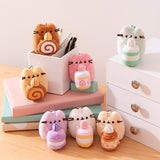 Alternate view of Pusheen Sweets Surprise Plush assortment. Plush keychains sit on multi-level pedestal in front of a office desk set-up. The mini plush Pusheens have a lobster claw clip for easy attachment to bags and zippers.