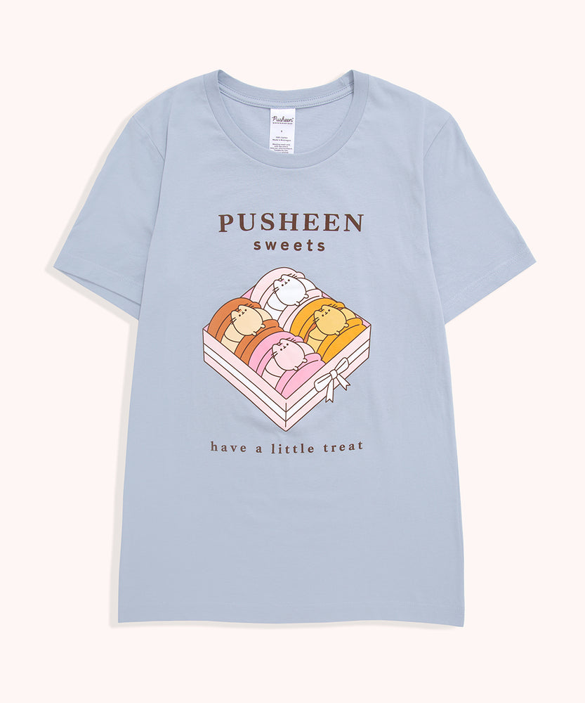 Blue t-shirt with a large graphic on the front center. The graphic shows Pusheen the Cat as four different types of macaron flavors placed in a box.