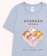 Close-up view of macaron graphic on the Sweet tee. The light pink box contains a brown chocolate, white and pink vanilla, toasted yellow caramel, and pink strawberry macarons. The light pink box is tied up with a white bow.