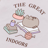 A close-up view of The Great Indoors Tee's screen print graphic. Pusheen lies on an open book while surrounded by more books, a yarn ball, and a plant. Above and below the Pusheen graphic is the phrases “The Great Indoors.” All print elements include the colors Grey, brown, yellow, orange, , green, and white. 