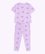 The Twilights Pajama Pants are laid out to show the full length of the pants. The pants are covered in a pattern of Pusheen with purple features, white crescent moons, pink hearts, and light purple rounded star shapes. 