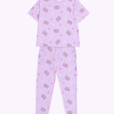 The Twilights Pajama Pants are laid out to show the full length of the pants. The pants are covered in a pattern of Pusheen with purple features, white crescent moons, pink hearts, and light purple rounded star shapes. 