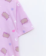 A close-up view of the Snack Time Pajama Tee sleeve. The relaxed-fit pajama shirt features a graphic of Pusheen with purple features surrounded by white crescent moons, light purple stars, and pink hearts.  