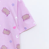 A close-up view of the Snack Time Pajama Tee sleeve. The relaxed-fit pajama shirt features a graphic of Pusheen with purple features surrounded by white crescent moons, light purple stars, and pink hearts.  