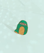 Pusheen Year of the Snake Pin. Pusheen wears a yellow and green snake costume. The green snake has yellow belly and tail details. The middle of the pin has scale details in gold plating.