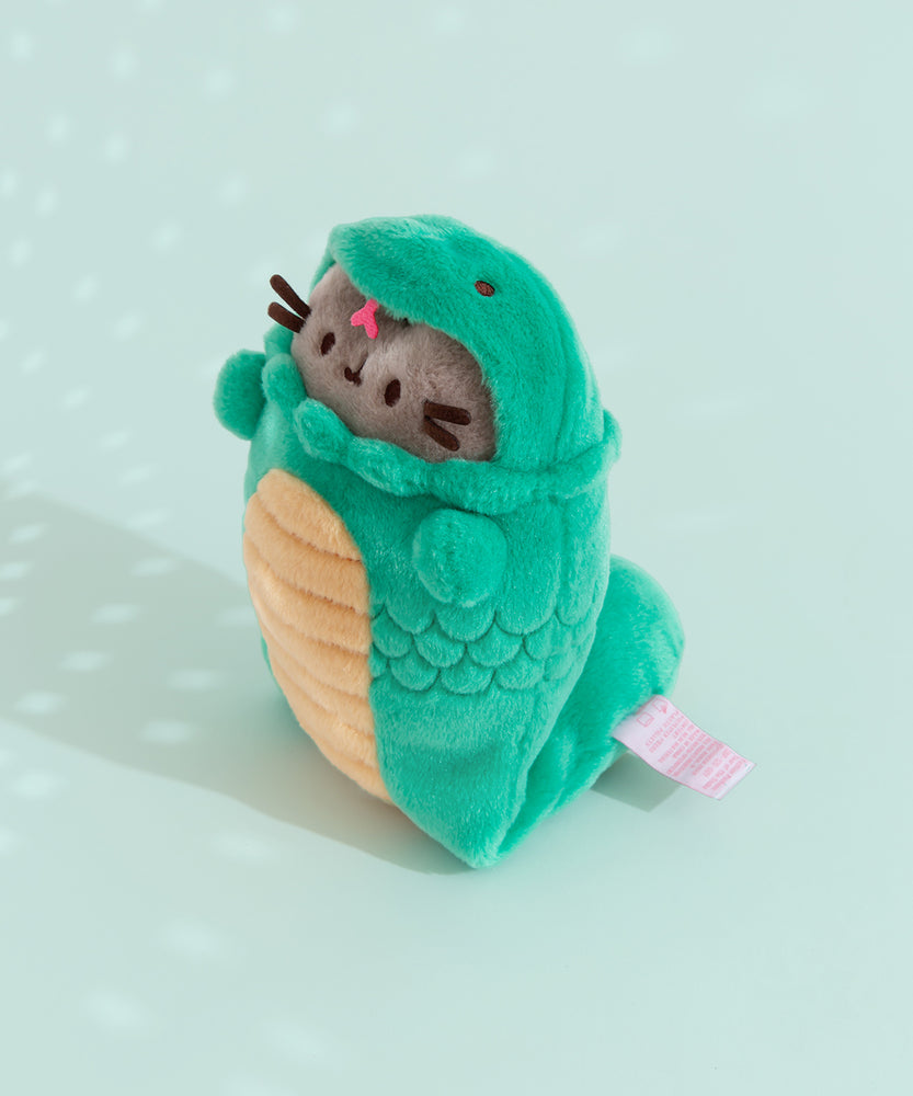 Quarter side view of Year of the Snake Plush. Pusheen the Cat wears a green and yellow snake costume that has a hood with two embroidered snake eyes and a pink felt tongue. 