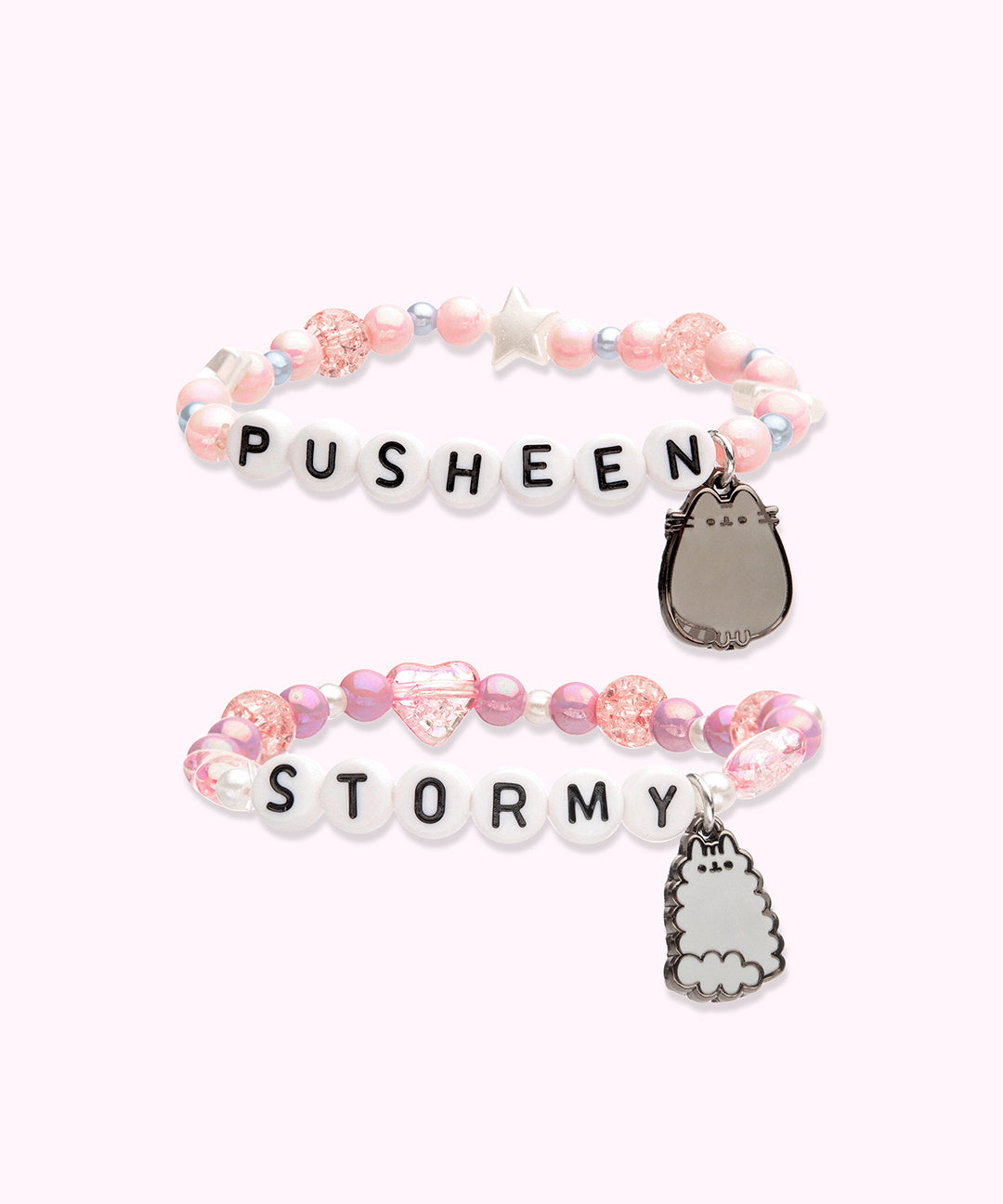 Front view of the Pusheen and Stormy Best Friends Bracelet Set. One of the bracelets has light pink round beads in varying sizes paired with white stars and silver beads with the letters “PUSHEEN” spelled out in beads in the middle and a dangle charm of Pusheen the Cat. The second bracelet has a dangle charm of Little Sister Stormy with purple round beads, pink heart beads, and white small beads. In the middle of the second bracelet is “STORMY” spelled out in letter beads. 