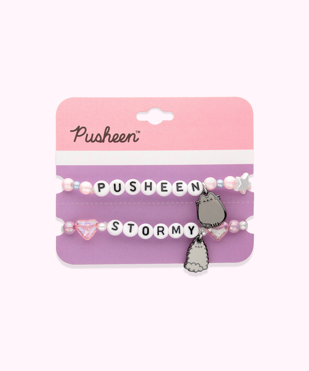 Pusheen & Stormy Best Friends Bracelet Set on its cardboard backing card. The top half of the card has the Pusheen logo in brown on a light pink background and the bottom half of the card is purple. Between the two bracelets is a perforated line to separate the backing card into two pieces. 