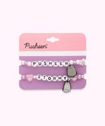 Pusheen & Stormy Best Friends Bracelet Set on its cardboard backing card. The top half of the card has the Pusheen logo in brown on a light pink background and the bottom half of the card is purple. Between the two bracelets is a perforated line to separate the backing card into two pieces. 