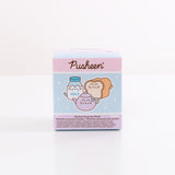 A close-up of the Pusheen’s Kitchen Surprise Plush packaging. The front of the packaging features Pusheen as various kitchen essentials including a white and blue milk jug, cream and light brown white bread slice, and lilac-colored tea pot. The packaging says "Kitchen Surprise Plush.” 