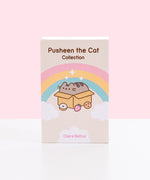 Front view of the Pusheen the Cat Collection: 3-Book Boxed Set. The decorative exterior storage box features the title of the boxed set. Below the title is a graphic of Pusheen laying inside a cardboard box while surrounded by a donut, strawberry, and chocolate chip cookie. Around Pusheen is a pink, yellow, and blue rainbow and white fluffy clouds and sparkles. At the bottom of the box is text stating the author, Claire Belton. 