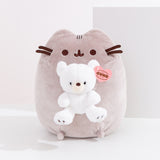 Front view of Pusheen x GUND Kai Bear Plush. The tabby cat sits upright holding a snow-white Kai bear, which is detailed with a cream-colored muzzle and embroidered paw pads.
