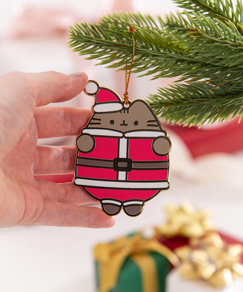 Model holds edge of holiday Pusheen ornament to show size and scale of the festive accessory.