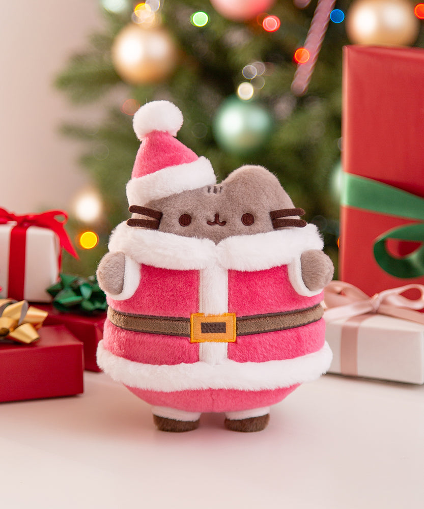 Santa Paws Pusheen plush toy showcases a tabby cat in a Santa outfit with Christmas decorations in the background.