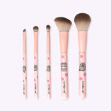 Front view of the The Creme Shop x Pusheen 5-pc Makeup Brush Set. The brushes have light pink printed barrels and handles with Pusheen graphics printed on the handles. The synthetic brush bristles are light brown to medium brown ombre towards the tips.