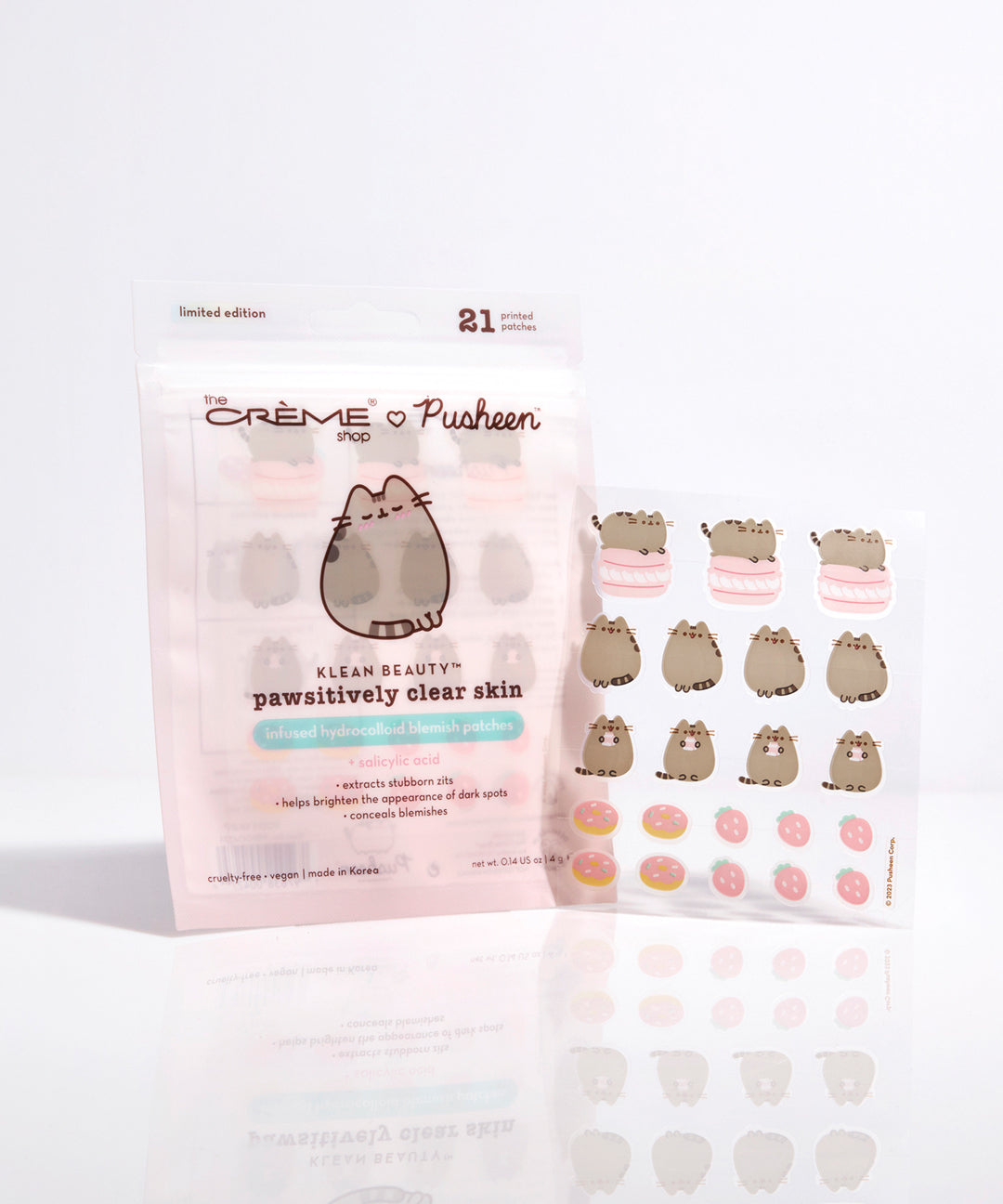 Front view of Pusheen Blemish patches packaging and blemish sheet. The set includes 21 printed patches of Pusheen, Pusheen on top of a macaron, sprinkled donuts, and strawberries.