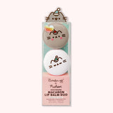 Holiday Macaron Lip Balm in its packaging. Printed on the front of the packaging is The Creme Shop and Pusheen logos as well as a few product ingredients including hyaluronic acid and murumuru.
