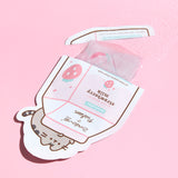 Pusheen Sheet Mask opened to show the translucent mask and serum included in the packet. The graphic on the packet shows Pusheen the Cat atop a strawberry milk carton. 