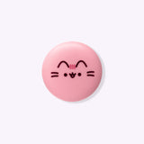Front view of the lip balm container. The pink circular component has Pusheen's face and facial features printed in brown and pink on the front.