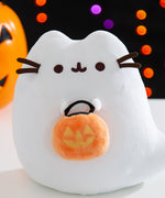 Close-up view of the Boosheen Halloween Light-Up Plush. The white ghost has Pusheen's classic eyes and mouth embroidered in dark brown. Pusheen the Cat's four 3D whiskers, two per side, extend off the plush sides. 